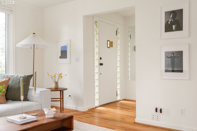 foyer entrance featuring light wood-type flooring, baseboards, and crown molding