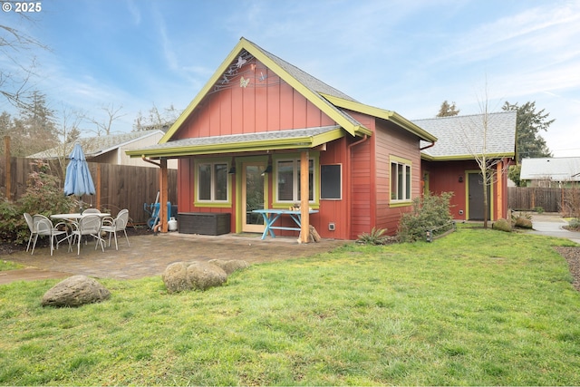 back of property featuring a patio, a shingled roof, a lawn, board and batten siding, and fence