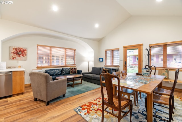 dining room with light wood-type flooring, high vaulted ceiling, arched walkways, and recessed lighting