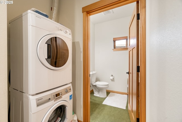 washroom featuring laundry area, carpet flooring, stacked washer and clothes dryer, and baseboards