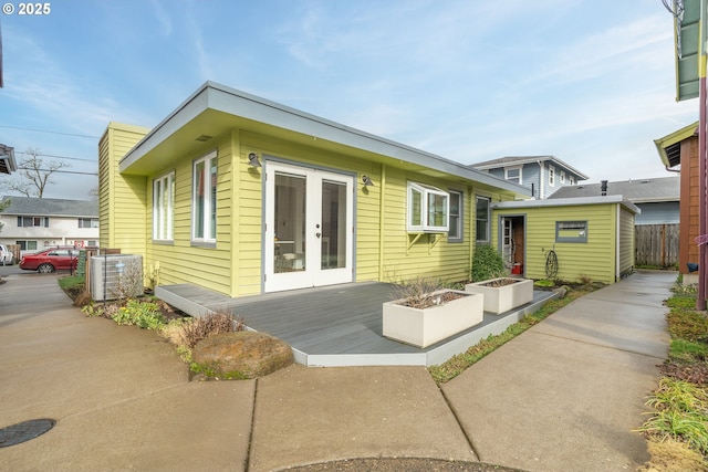 rear view of house with an outbuilding, french doors, central AC unit, fence, and a deck