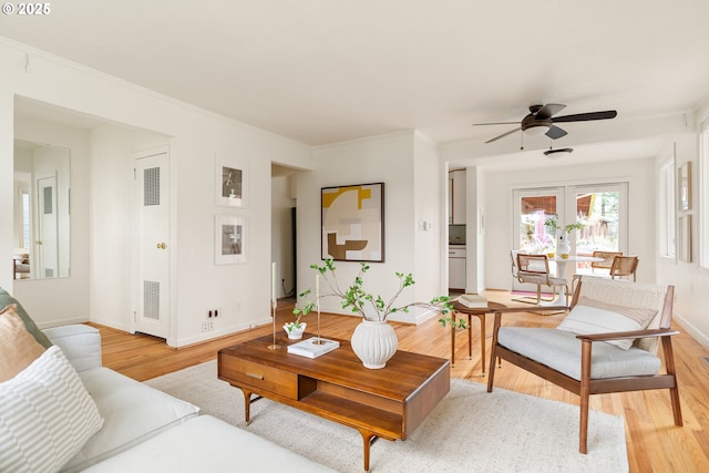 living area with baseboards, light wood finished floors, and crown molding