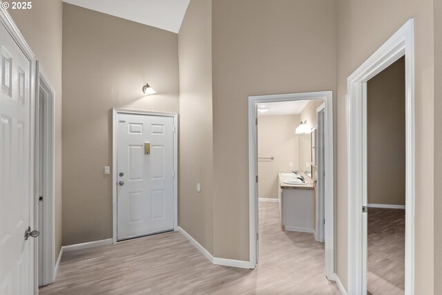 foyer with light wood-type flooring, vaulted ceiling, and sink