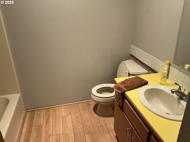 bathroom with vanity, a tub to relax in, hardwood / wood-style flooring, and toilet