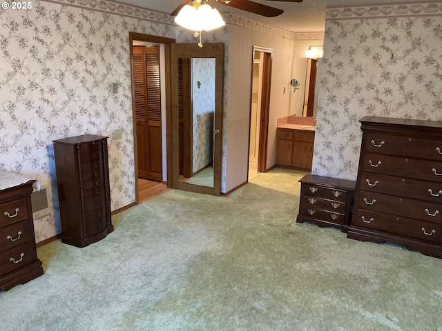 bedroom featuring connected bathroom, light colored carpet, and ceiling fan