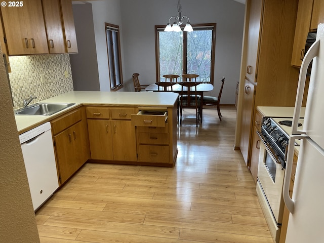 kitchen with pendant lighting, sink, white appliances, light hardwood / wood-style flooring, and kitchen peninsula