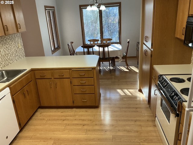 kitchen with light hardwood / wood-style flooring, decorative light fixtures, white appliances, and kitchen peninsula