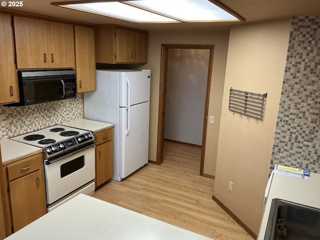 kitchen with white appliances, decorative backsplash, and light wood-type flooring