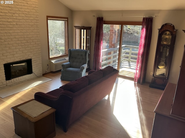 living room featuring lofted ceiling, a brick fireplace, and light hardwood / wood-style flooring