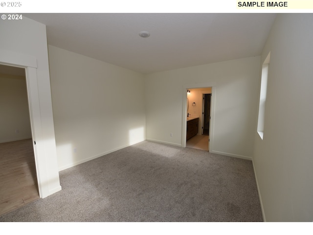 empty room featuring baseboards and light carpet