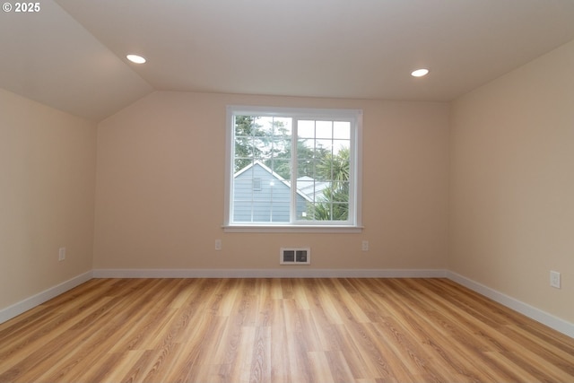 additional living space featuring visible vents, light wood-style flooring, baseboards, and vaulted ceiling