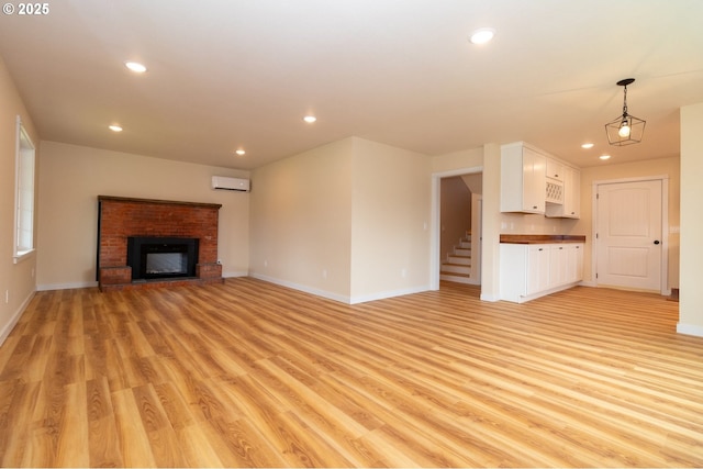 unfurnished living room featuring recessed lighting, baseboards, and a wall unit AC