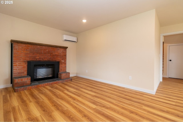 unfurnished living room featuring baseboards, a fireplace, light wood-type flooring, and a wall mounted air conditioner