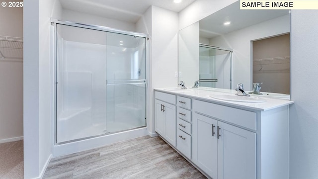 2131 NE 3rd Ave, Battle Ground, WA 98604 - bathroom with a walk in closet, double vanity, a stall shower, wood finished floors, and recessed lighting