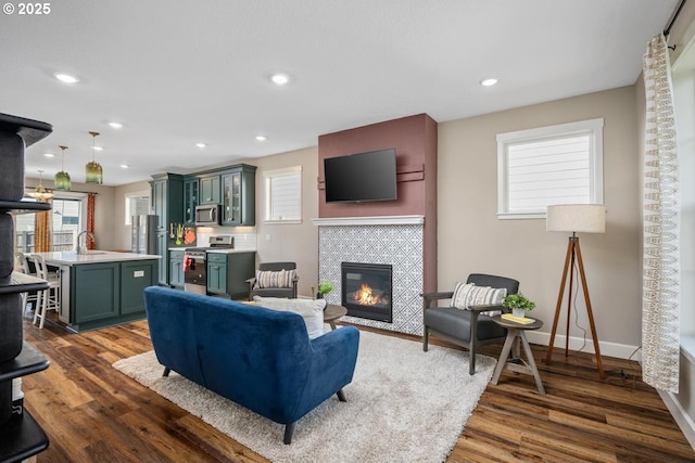 living room with a tiled fireplace, sink, and dark hardwood / wood-style flooring