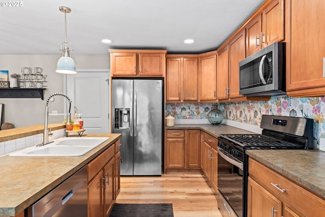 kitchen with pendant lighting, stainless steel appliances, sink, and decorative backsplash