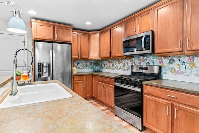 kitchen featuring hanging light fixtures, appliances with stainless steel finishes, sink, and light wood-type flooring