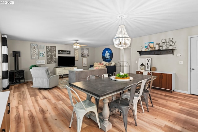 dining room featuring a wood stove, ceiling fan, and light hardwood / wood-style flooring