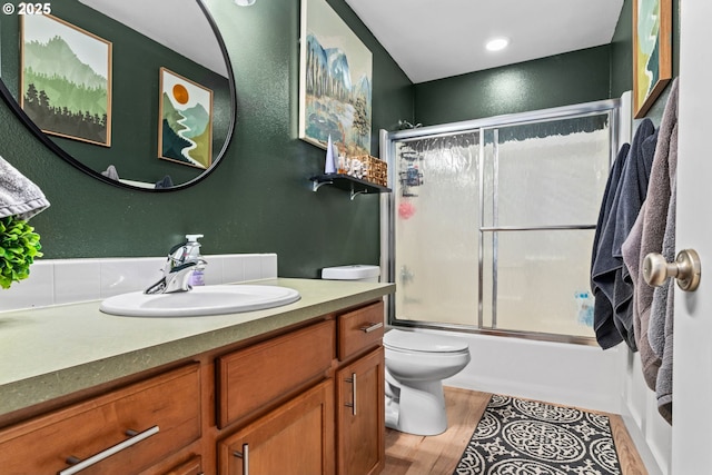 full bathroom featuring vanity, hardwood / wood-style flooring, toilet, and combined bath / shower with glass door