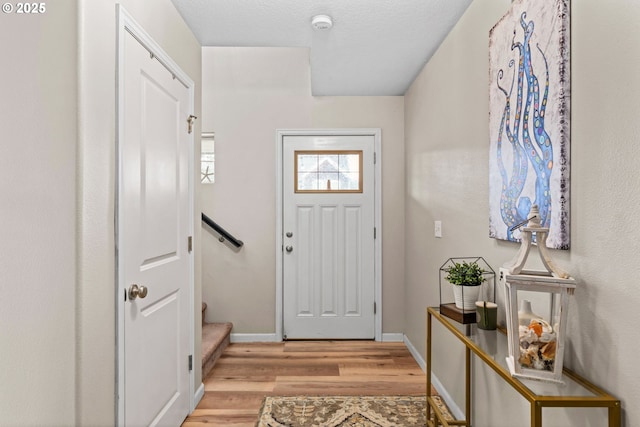 doorway to outside with a textured ceiling and light wood-type flooring