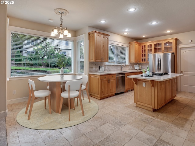 3808 Fairhaven Dr, West Linn, OR 97068 - kitchen with appliances with stainless steel finishes, a kitchen island, light countertops, backsplash, and glass insert cabinets