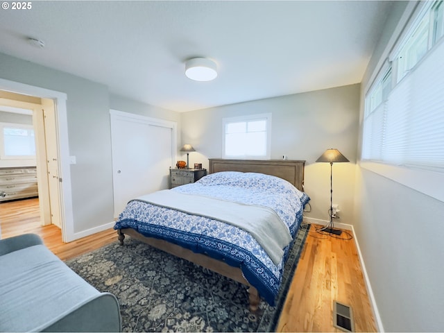 bedroom featuring a closet, visible vents, baseboards, and wood finished floors