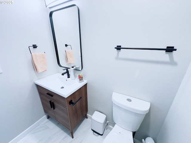 bathroom with toilet, vanity, marble finish floor, and baseboards