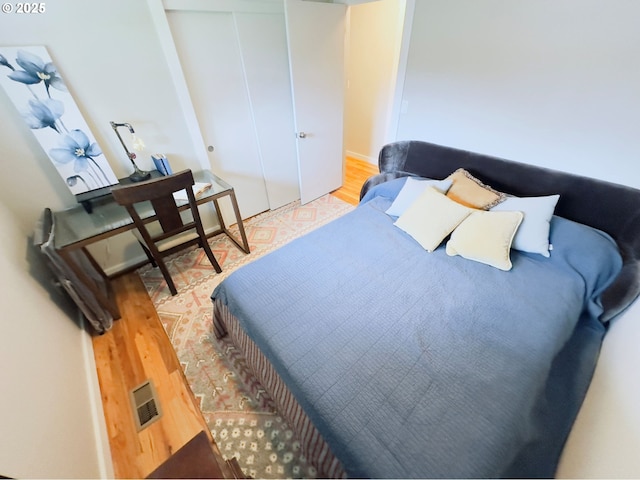 bedroom with visible vents, a closet, and wood finished floors