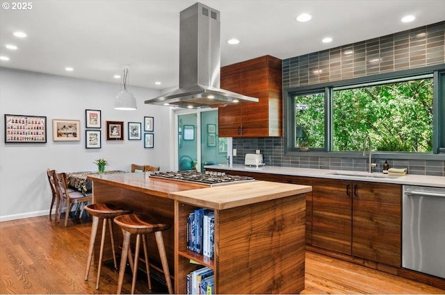 2975 SW Canterbury Ln, Portland, OR 97205 - kitchen featuring island range hood, stainless steel appliances, wooden counters, a sink, and tasteful backsplash