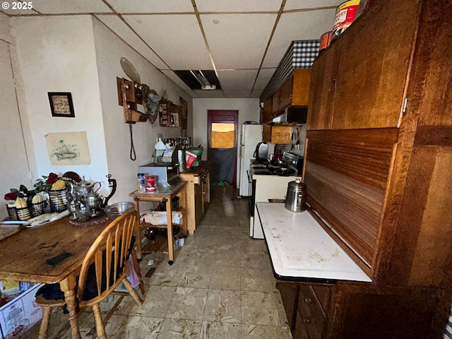 kitchen featuring white refrigerator, range with electric stovetop, and a drop ceiling