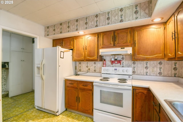 104 NW 12th St, Pendleton, OR 97801 - kitchen featuring white appliances, under cabinet range hood, light countertops, light floors, and brown cabinets