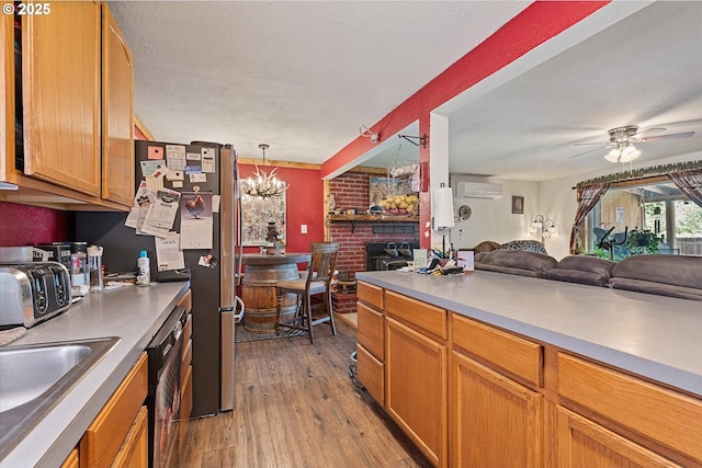kitchen featuring open floor plan, a wall mounted air conditioner, light wood finished floors, a ceiling fan, and a chandelier