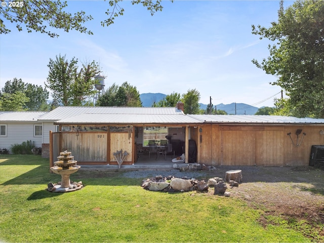 back of house with a yard, a metal roof, a chimney, and a mountain view