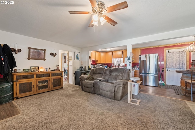 carpeted living area featuring ceiling fan and a chandelier