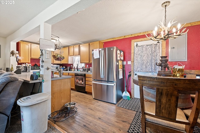 kitchen with freestanding refrigerator, black dishwasher, electric panel, a chandelier, and light wood-type flooring
