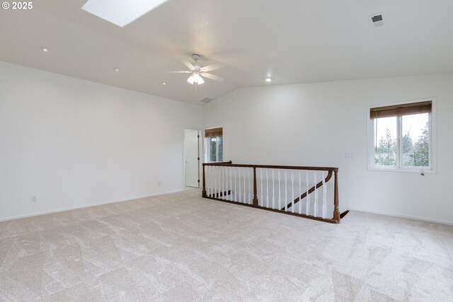 unfurnished room with lofted ceiling with skylight, visible vents, light carpet, and baseboards