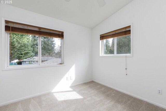 unfurnished room with light colored carpet, a ceiling fan, baseboards, and vaulted ceiling