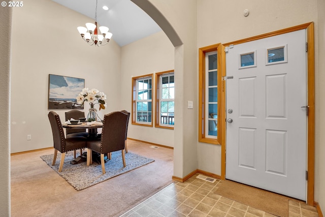 dining area featuring baseboards, a chandelier, carpet floors, arched walkways, and high vaulted ceiling