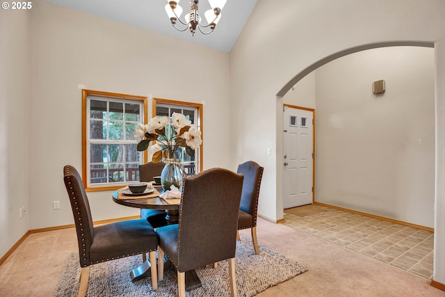 carpeted dining space featuring a notable chandelier, baseboards, arched walkways, and high vaulted ceiling