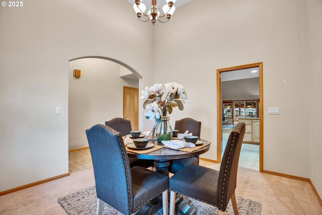 dining room featuring baseboards, carpet floors, a high ceiling, arched walkways, and a notable chandelier