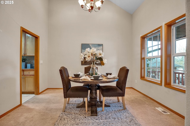 dining space with an inviting chandelier, light colored carpet, visible vents, and baseboards