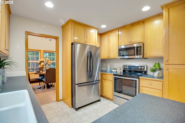 kitchen featuring light brown cabinets, baseboards, recessed lighting, a sink, and stainless steel appliances