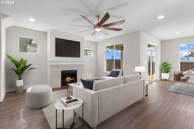 living room with dark hardwood / wood-style floors, ceiling fan, plenty of natural light, and a tiled fireplace