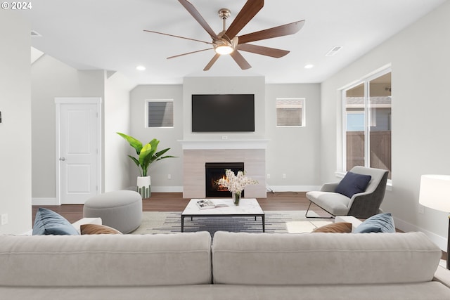 living room featuring ceiling fan, a tiled fireplace, and wood-type flooring