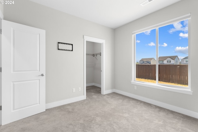 unfurnished bedroom with light colored carpet, a closet, and a walk in closet