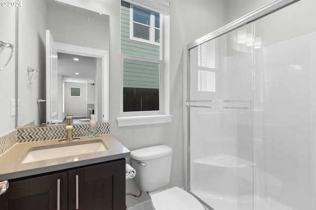 bathroom with an enclosed shower, vanity, and toilet