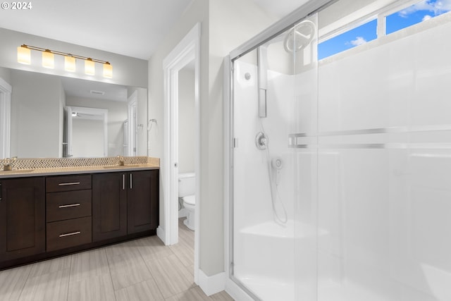 bathroom featuring toilet, an enclosed shower, and vanity