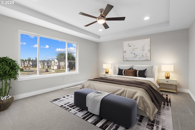 carpeted bedroom featuring ceiling fan, a tray ceiling, and multiple windows