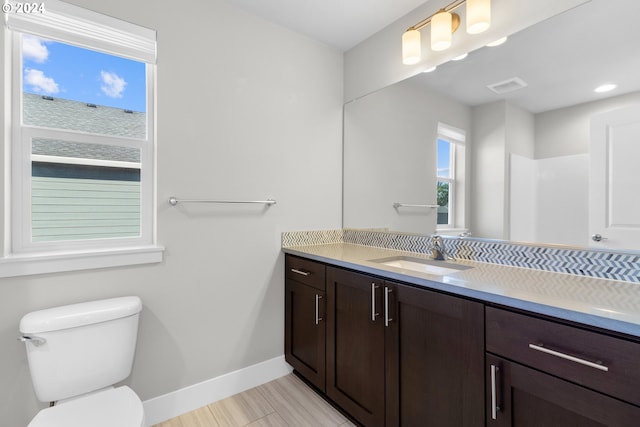 bathroom featuring toilet, vanity, and a shower