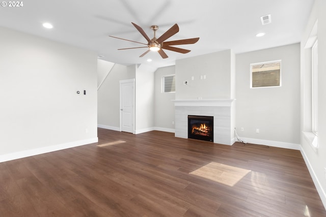 unfurnished living room featuring dark wood-type flooring, ceiling fan, a healthy amount of sunlight, and a fireplace